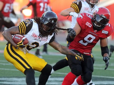 Tit for Tat. Calgary Stampeders Jon Cornish gives a tug on the Hamilton Tiger-Cats Johnny Sears Jr. during their season opener at McMahon Stadium, on June 26, 2015.