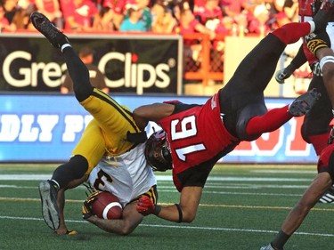 Calgary Stampeders Marquay McDaniel takes down the Hamilton Tiger-Cats Johnny Sears Jr. during their season opener at McMahon Stadium, on June 26, 2015.