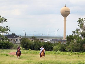 A couple of band members ride horses near the Multipurpose Building in Stand Off on the Blood Reserve.