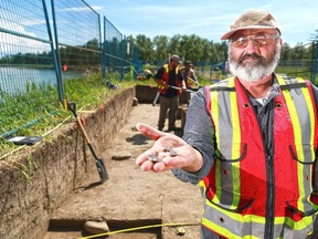 Archeologist Dan Meyer holds up small tools a flint and an arrowhead at an archeological dig site along the Bow River in Fish Creek Provincial Park on Tuesday.