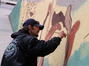 Artist Ryan Delve works on a mural along a concrete wall outside the Drop-In Centre in Calgary on Thursday May 29, 2014. Delve was found dead on Thursday, June 4th, 2015, the victim of a homicide.