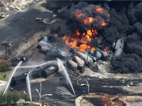 In this July 6, 2013 file photo, smoke rises from railway cars carrying crude oil after derailing in downtown Lac Megantic, Que.