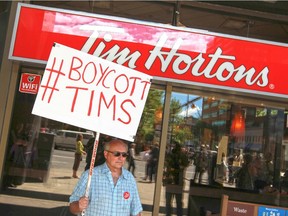 A man protests outside a Tim Hortons in Calgary's Beltline after the company pulled an in-store Enbridge ad.