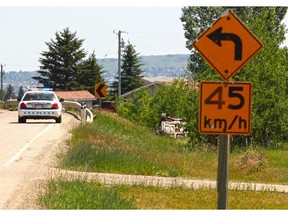 RCMP investigate the scene where a vehicle left the road and rolled at a corner on Highway 566 just north of Calgary on Saturday, June 27, 2015.