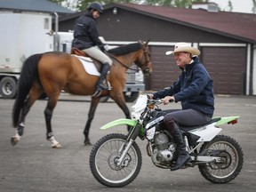 Canadian equestrian legend Ian Millar, from Perth, Ont., rides a dirt bike in the stables area at Spruce Meadows on Tuesday.