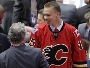 Pavel Karnaukhov puts on a Flames jersey after being chosen 136th overall by Calgary during the fifth round of the NHL draft  on Saturday, in Sunrise, Fla.