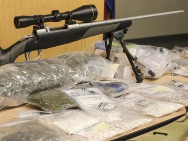 A scoped rifle along with prescription and illegal drugs are shown at a police press conference following an arrest at the Calgary Police Headquarters in Calgary on Thursday, June 4, 2015.