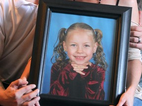 Meika Jordan's stepfather, Brian Woodhouse, and mother, Kyla Guttman,  show a photo of the six-year-old  who was slain by her father and stepmother.