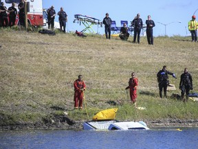 Rescue teams tow out a truck that drove into the water near the intersection of Glenmore Trail SE and Stoney Trail SE in Calgary, on June 20, 2015.  A man had been pulled out of the vehicle but later died in hospital.