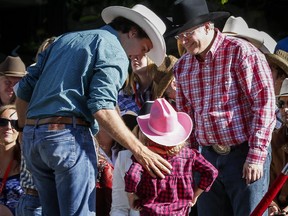 Prime Minister Stephen Harper, right, meets Liberal leader Justin Trudeau, left, and his daughter Ella-Grace while attending the Calgary Stampede parade, Friday, July 4, 2014.