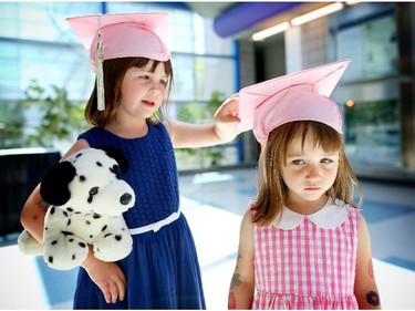 Isla Bolin, 4, left and her sister Neve, 3, fix their caps as they wait to watch their mom graduate with a master's degree at the university of Calgary's convocation on june 8, 2015.
