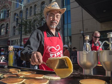 Ken Onizaki, centre, flips pancakes for Calgary Economic Development's sixth annual First Flip on Stephen Avenue in Calgary on Thursday.