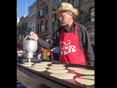 Ken Onizaki, centre, pours pancake batter for Calgary Economic Development's sixth annual First Flip on Stephen Avenue in Calgary on Thursday.