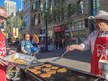 Lyle Kent, left, receives a flipped pancake from Mayor Naheed Nenshi at the Calgary Economic Development sixth annual First Flip on Stephen Avenue in Calgary on Thursday, July 2.