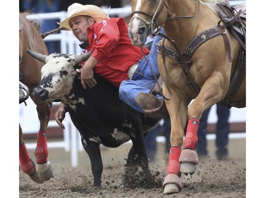 Bray Armes tackles his way to a fifth place finish during day three steer wrestling action at the 2015 Calgary Stampede, on July 5, 2015.