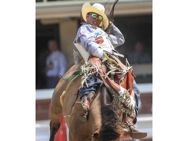 Ritchie Champion holds his on as he rides Big Foot to a tenth place finish during Day 9 of bareback rodeo action at the 2015 Calgary Stampede,, on July 11, 2015.