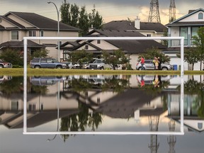 Neighbors congregate on the ridge to a flooded field next to Prairie Waters Elementary School in Chestermere on Tuesday, July 14.