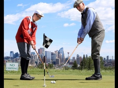 Tyler Thurston, 15, and Bob Clarke work on their putting with their period dress and their hickory clubs in celebration of 100 years at city of Calgary's Shaganappi Point Golf Course, in Calgary, on July 28, 2015.