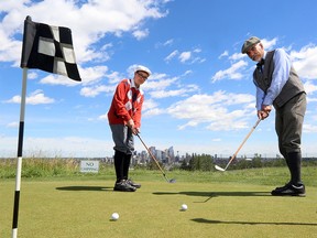 Tyler Thurston, 15, and Bob Clarke work on their putting with their period dress and their hickory clubs in celebration of 100 years at the City of Calgary's Shaganappi Point Golf Course, on July 28, 2015.