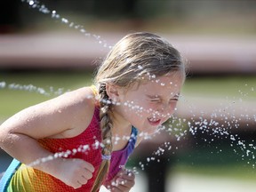 Calgary's Camryn Hewitt, 4, beat the heat by playing in the cool spray at the newly reopened South Glenmore Park Spray Park with her family on July 31, 2015. Temperatures were expected to reach 30C and stay warm through the weekend.