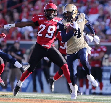 Winnipeg Blue Bombers Darvin Adams, right, runs the ball in for a touchdown as Calgary Stampeders' Jamar Wall, left, looks on during their game at McMahon Stadium on July 18, 2015.