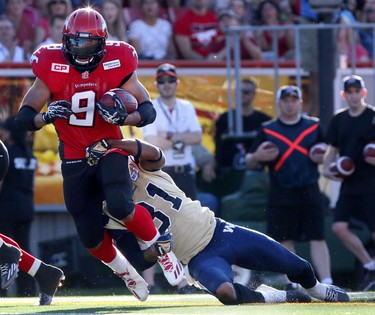 Calgary Stampeders Jon Cornish, left, tries to evade a tackle from Winnipeg Blue Bombers Maurice Leggett during their game at McMahon Stadium on July 18, 2015.