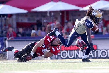 Winnipeg Blue Bombers Troy Stoudermire, right, and Calgary Stampeders Rob Cote, left, collide during their game at McMahon Stadium on July 18, 2015.