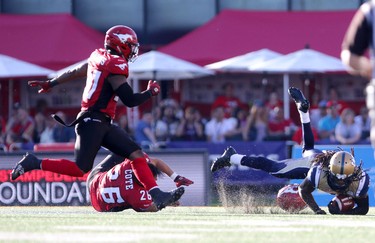 Winnipeg Blue Bombers Troy Stoudermire, right, is tackled by Calgary Stampeders Rob Cote, middle, during their game at McMahon Stadium on July 18, 2015.