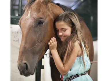 Ameliana Horb shares a moment with Tucker, a horse owned by Roger Moore, at the barns behind the Grandstand on July 11.