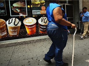 A woman walks by a sign advertising sugary drinks in a Brooklyn neighborhood with a high rate of obesity and diabetes on June 11, 2013 in New York City.  Families trying to lose weight often run into 'blind spots.'