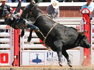 Scott Schiffner from Strathmore AB flies off Cooper King while competing in the bull riding event during day 1 of the Calgary Stampede rodeo on  Friday July 3, 2015.