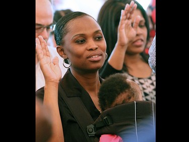 Originally from Nigeria, Olayemi Olabiyi performs the oath of Canadian citizenship with about 75 other new Canadians in a Canada Day citizenship ceremony at Heritage Park.