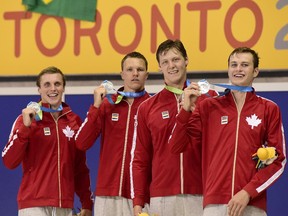 Canadian team members Santo Condorelli, left, Karl Krug, Evan Van Moerkerke and Yuri Kisil smile as they hold their medals after a second place finish in the men's 4x100 freestyle swimming event at the Pan Am Games in Toronto on Tuesday. Both Krug and Kisil are from Calgary.