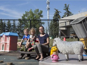 Carol Roesler, right, is pictured with her children Sophie, 3, and Lukas , 5, in the playground area of their daycare, where a cell phone tower, pictured in the background, has been placed in Calgary, on July 2, 2015.