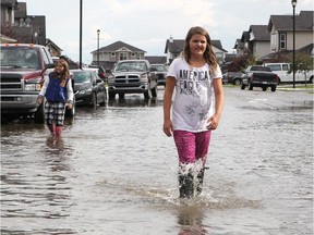 Taya MacLeod, right, and Sydney Saraceni walked through the flooded Willowmere Way in Chestermere on July 14, 2015.