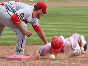 The Okotoks Dawgs' Brendan Rose beats the ball and Medicine Hat first baseman Andy Scott during a base stealing attempt in the team's final regular season home game at Seaman Stadium on Sunday July 26, 2015.