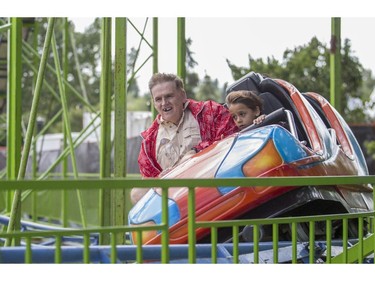 Steven Walsh, rides the mini roller coaster with his son Brady Biaci-Walsh, 5, during Family Day at the 2015 Calgary Stampede, on July 5, 2015.