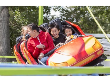 Selina Che, left, 19, takes her little brothers, Kurtis, centre, 7, and Theodore, on the mini roller coaster during Family Day at the 2015 Calgary Stampede, on July 5, 2015.