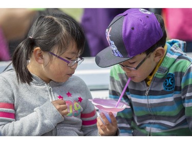 Nicole Gui, 8, left, and her brother, Albert, 10, share a slushy drink during Family Day at the 2015 Calgary Stampede, on July 5, 2015. -