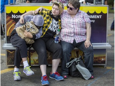 Deanna Bates, right, and her daughters, Sam, 15, centre and Saramae, take a well earned rest during Family Day at the 2015 Calgary Stampede, on July 5, 2015. -
