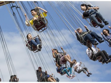 Marvin Miller, 11, yellow shirt, and his sister Amy, 16, behind left, ride the swings during Family Day at the 2015 Calgary Stampede, on July 5, 2015.