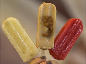 A a mini-donut popsicle is held up, centre,  along with other flavours at the Family Freezed frozen treat shop at the Calgary Stampede.