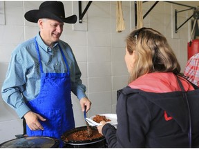Prime Minister Stephen Harper serves beans during a Stampede pancake breakfast at the Currie Barracks in Calgary, on July 7