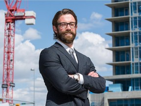 Ian Meredith, a residential expert with the  Altus Group, stands in front of two new condo developments in downtown Calgary.