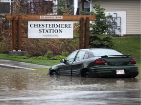 A car is left abandoned on Marina Drive due to flooding in Chestermere.