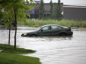 A car is left abandoned on Marina Drive due to flooding in Chestermere.