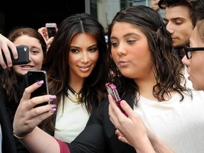 In this Friday, Sept. 21, 2012 file photo Kim Kardashian, left, is surrounded by her fans who are attempting to have their photographs taken with her as she leaves a radio station in Melbourne, Australia.