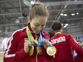 Calgary's Monique Sullivan inspects the three gold medals she won for women's sprint; women's kreirin and women's team sprint in track cycling at the Pan Am games.