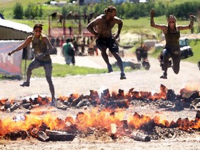 Kaila Maddalo, left, Mathew Dorsey and Amanda Blais jump the Pyromania at the Rugged Maniac run Saturday July 18, 2015 at Rocky Mountain Show Jumping. Hundreds of adventurers ran, climbed and slogging through a 5 kilometre course of ropes, towers, mud and fire.