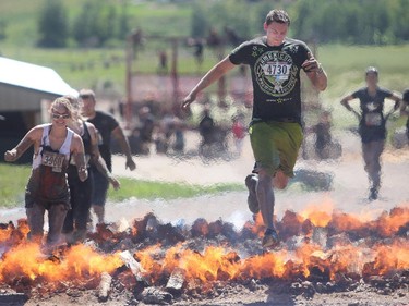 Bret McIvor leaps the flames on the Pyromaniac portion of the Rugged Maniac obstacle course Saturday July 18, 2015 at Rocky Mountain Show Jumping. Hundreds of adventurers ran, climbed and slogging through a 5 kilometre course of ropes, towers, mud and fire. The show travels across North America with it's next Canadian stop in Vancouver August 15.